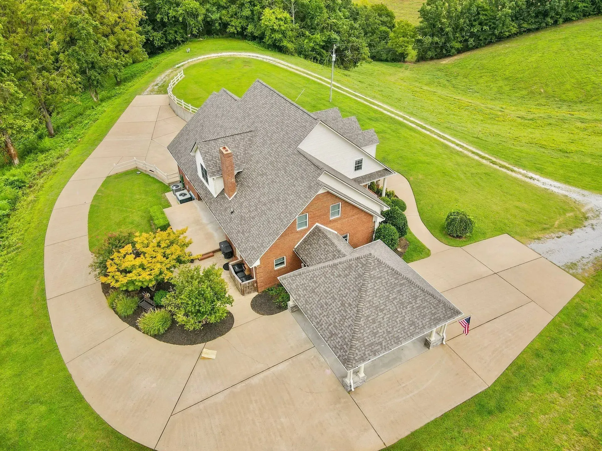 Aerial view of a suburban house with a curved driveway and green lawn.