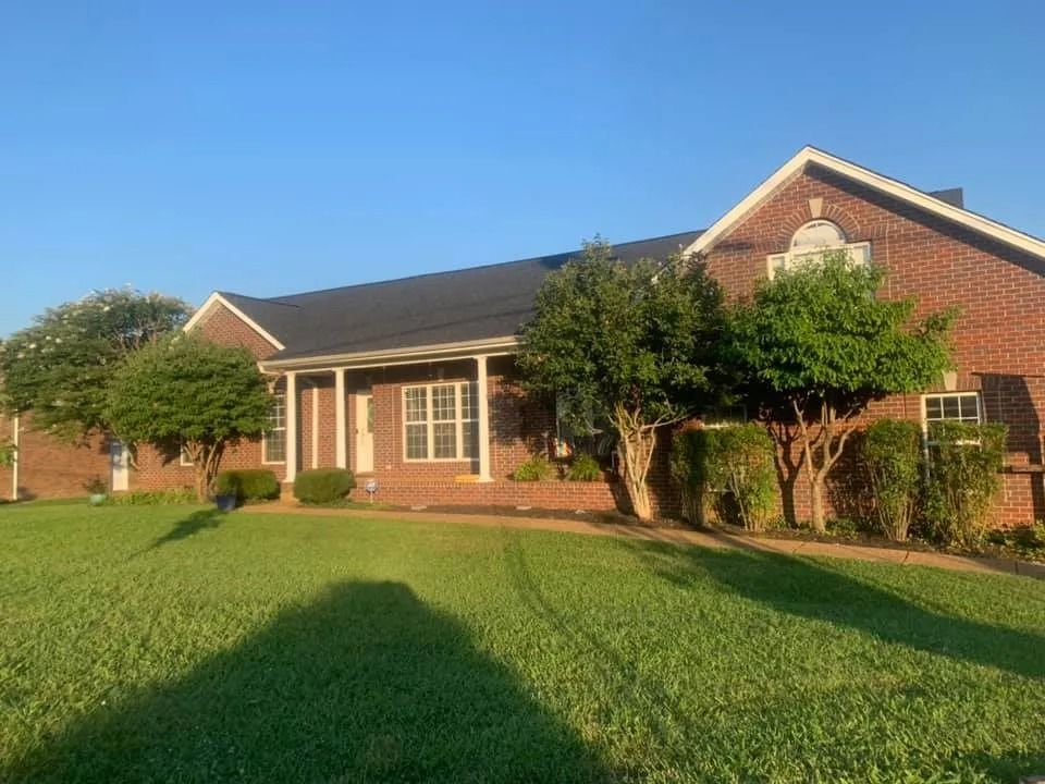 Brick house with manicured lawn and trees in warm sunlight