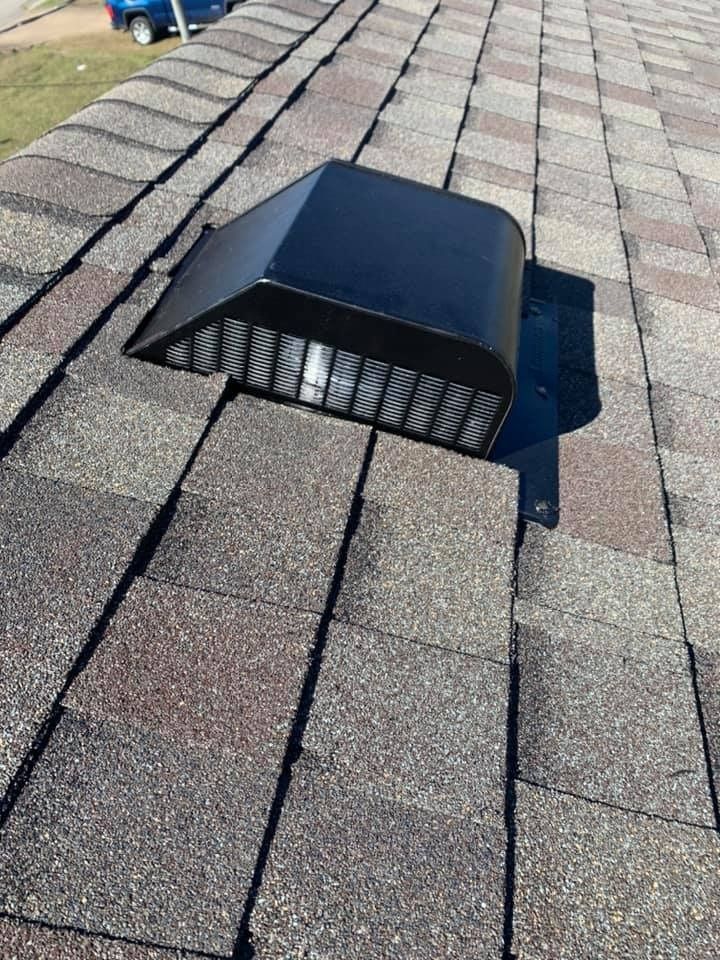 Black roof vent on asphalt shingle roof in sunlight