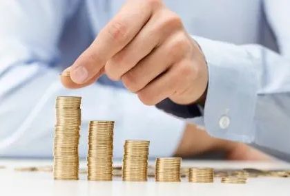 A man is stacking coins on top of each other on a table.