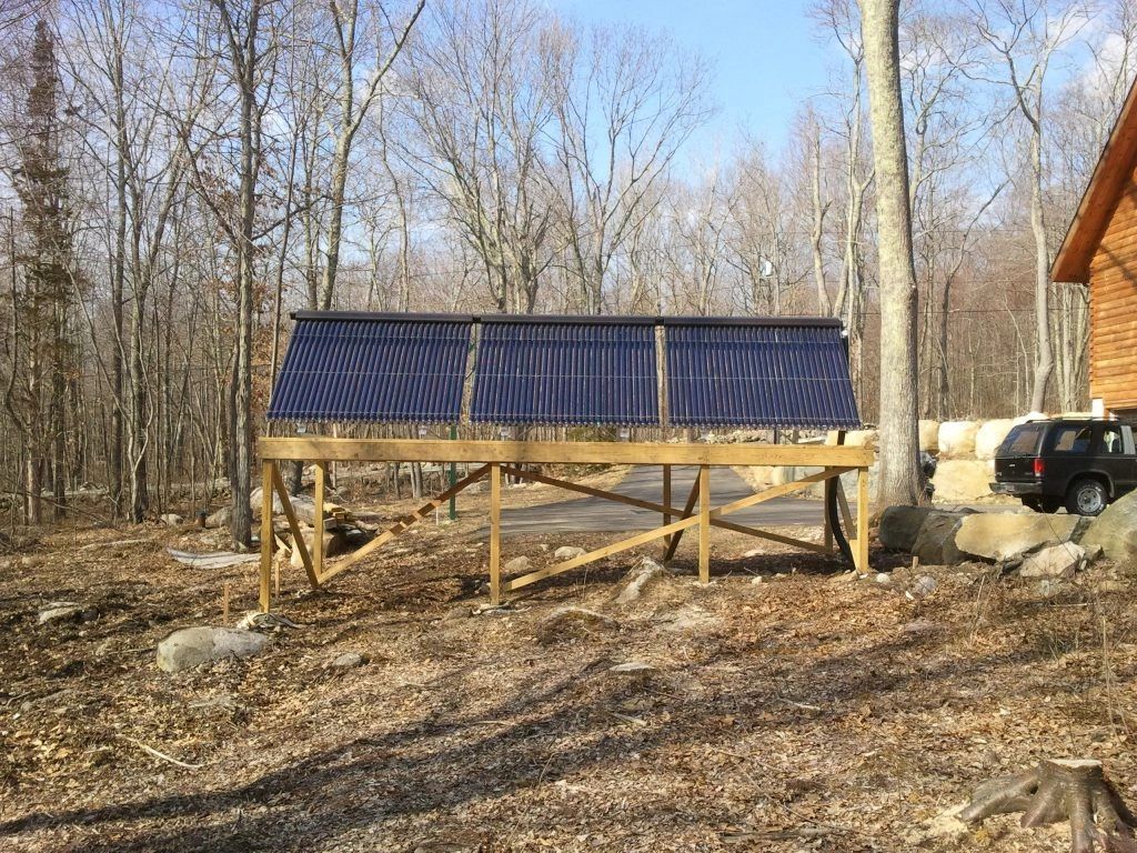 A row of solar panels are sitting on top of a wooden structure in the woods.
