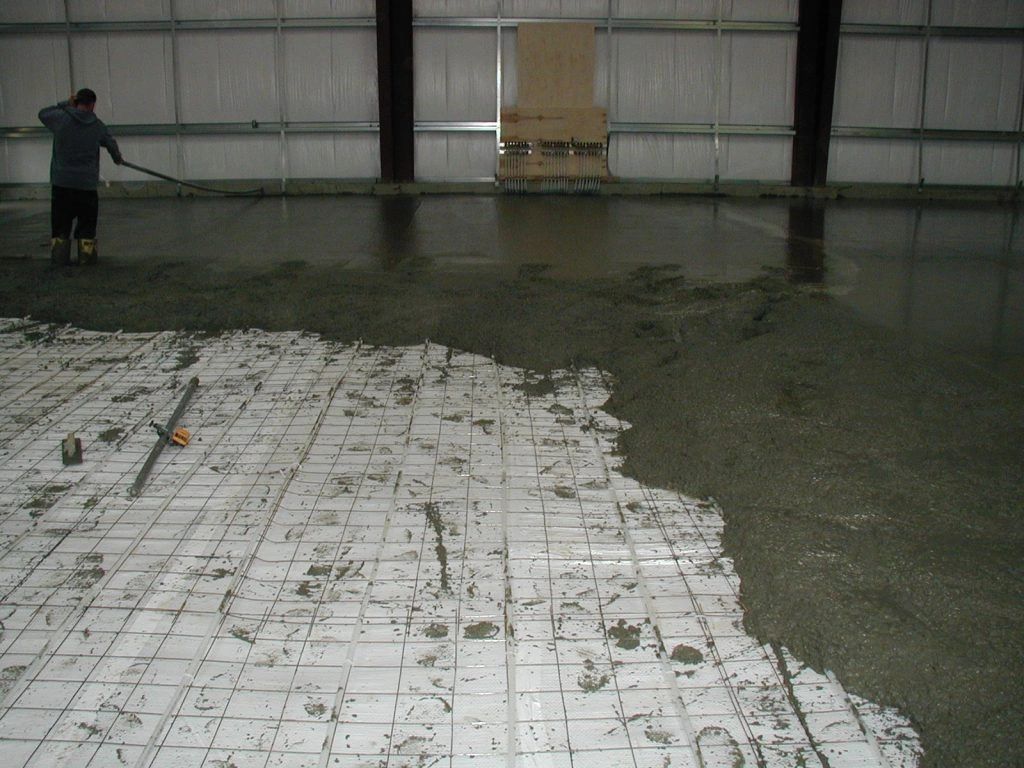 A man is spreading concrete on the floor of a building
