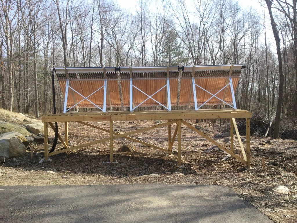 A wooden bench is sitting on a wooden platform in the middle of a forest.