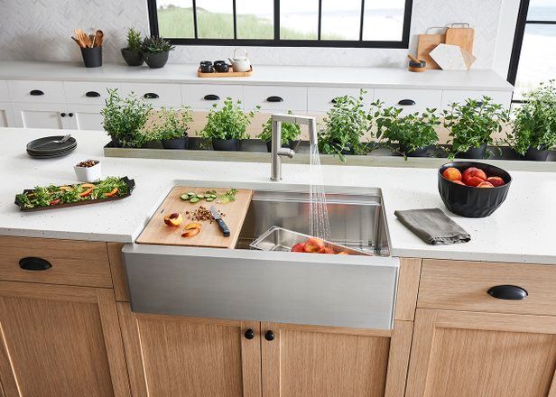 Stainless steel kitchen sink with cutting board and countertop with fresh produce.
