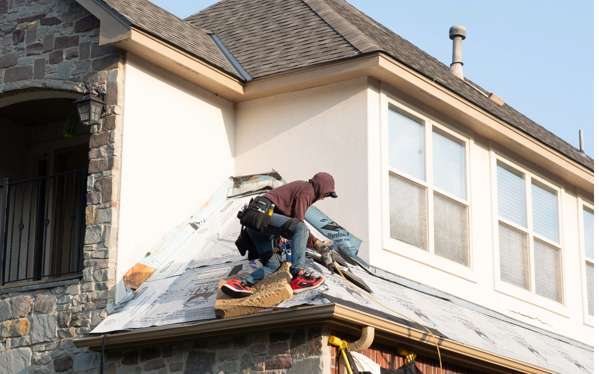A man is working on the roof of a house.