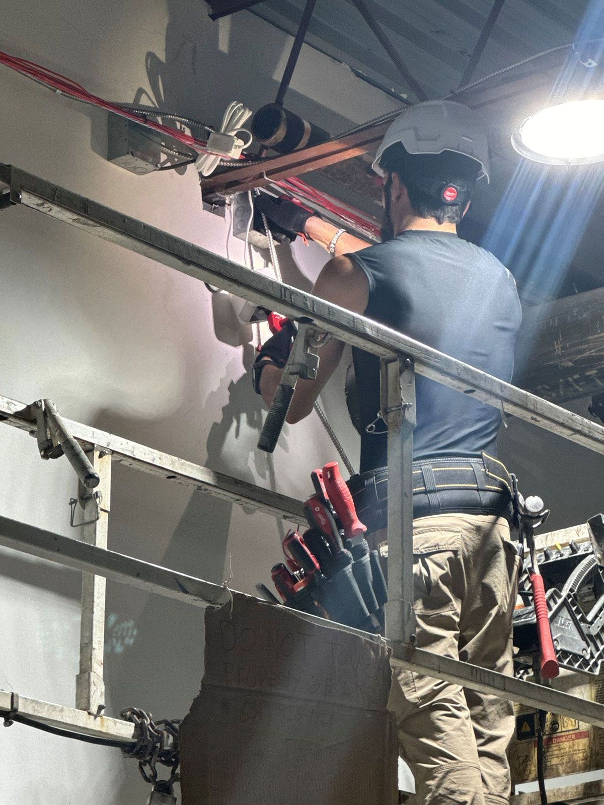 A man is standing on a railing working on a wall