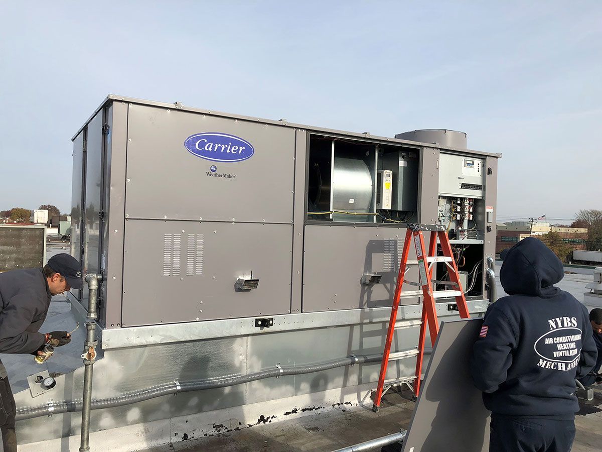 A carrier air conditioner is being installed on the roof of a building