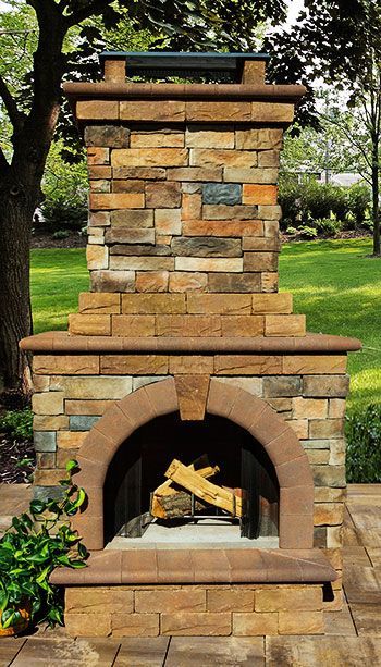 A stone fireplace with logs in it in a yard