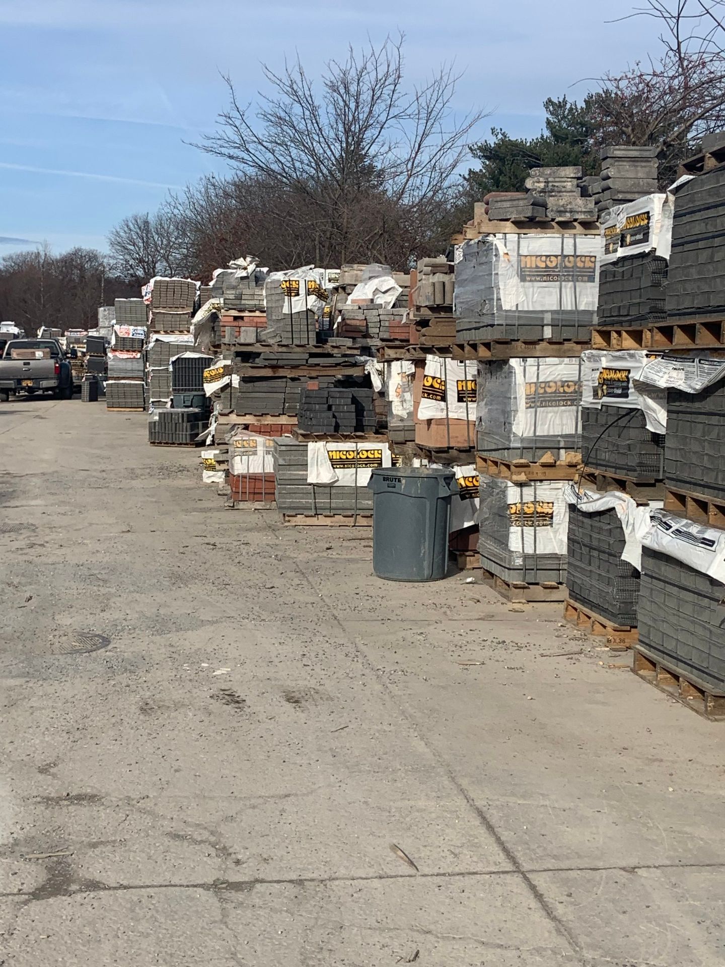 A lot of bricks are stacked on top of each other in a yard.
