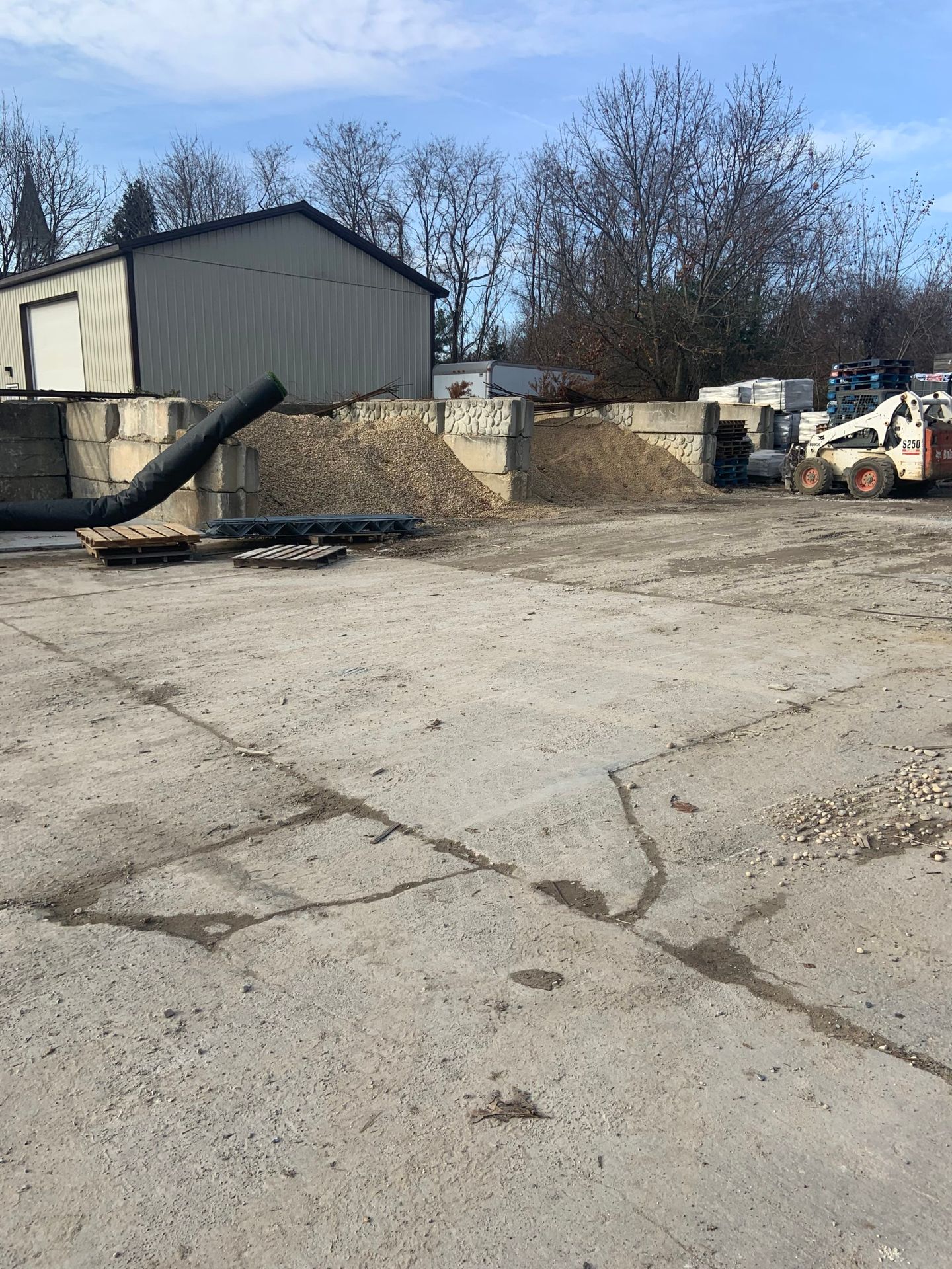A large concrete yard with a lot of machinery and a building in the background.