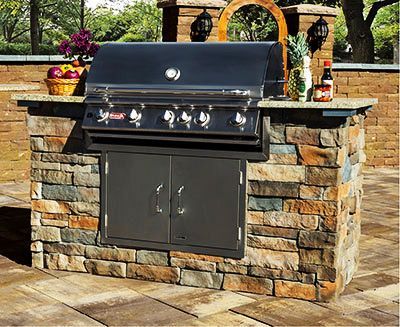 A grill is built into a stone wall on a patio.