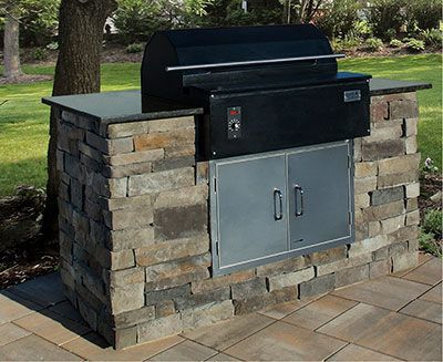 A grill is built into a stone wall on a patio