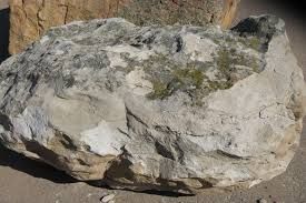 A large rock is sitting on top of a dirt field.