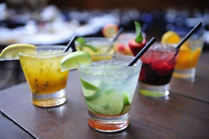 Colorful tropical cocktails with straws and lime wedges on a wooden table