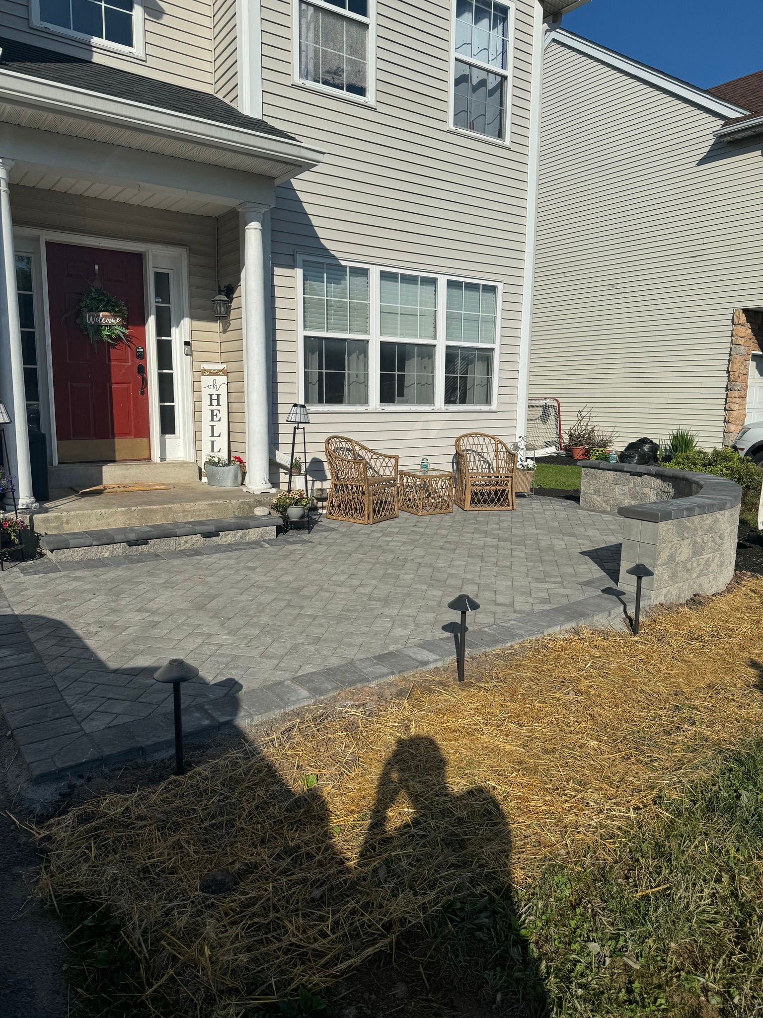 House exterior with a stone patio, chairs, and landscaping.