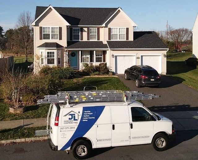 White van with ladder parked in front of a two-story house; a black car sits in the driveway.