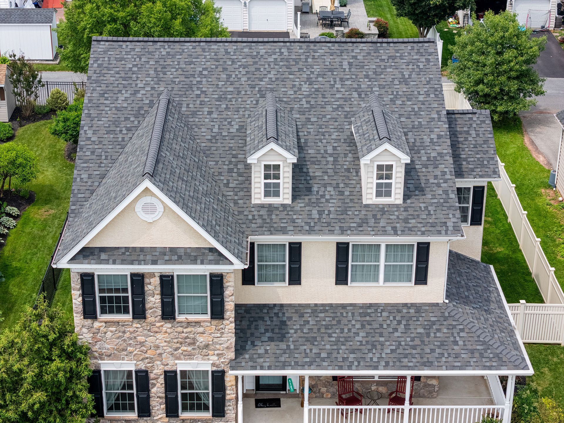 Two-story house with gray shingle roof, three dormer windows, and a porch.