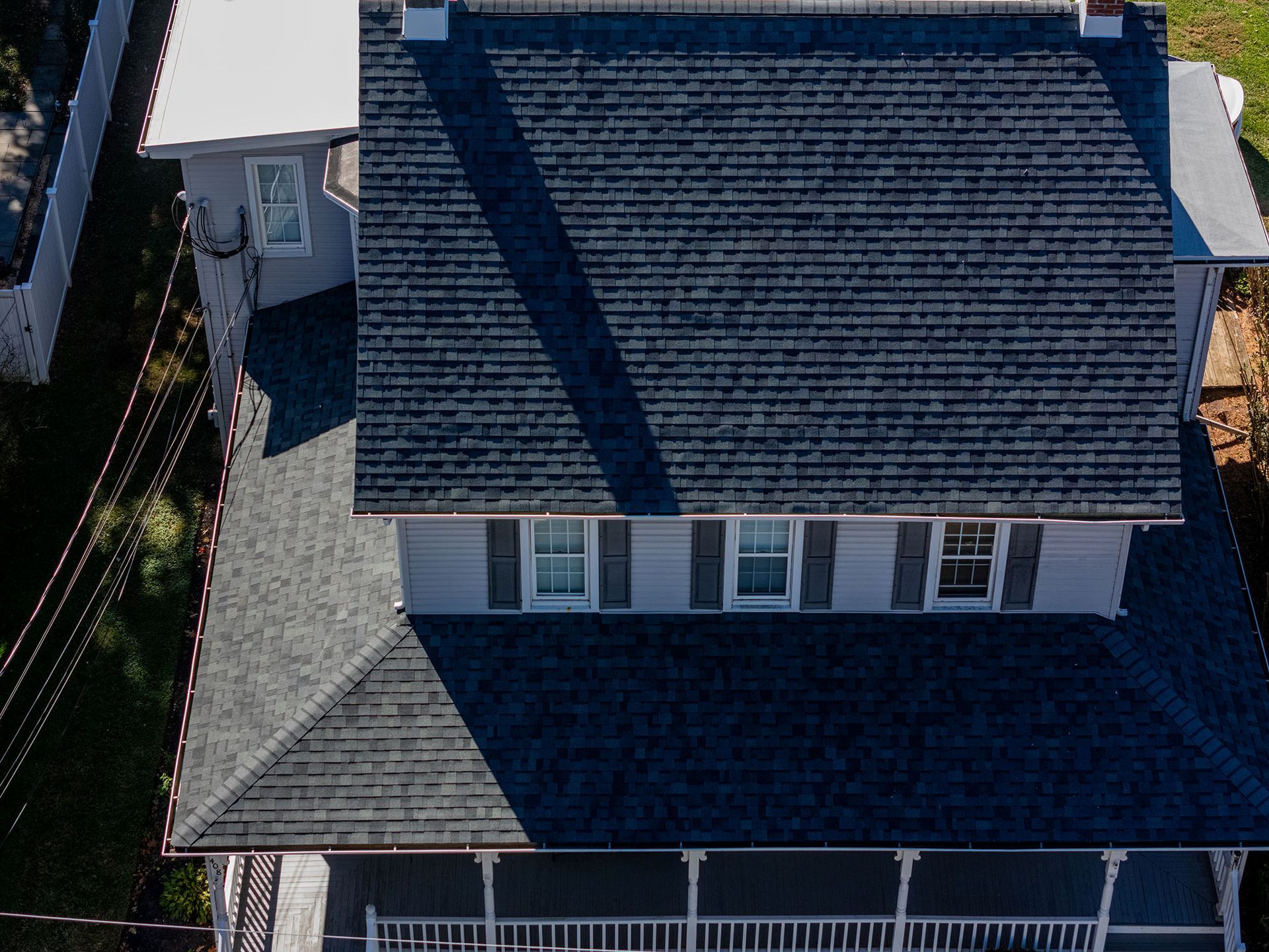 Overhead view of a gray house with a dark blue shingled roof, a porch, and several windows.