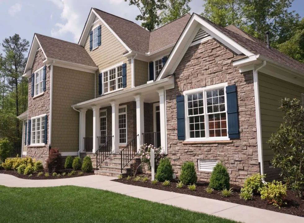 Two-story house with stone and tan siding, white trim, blue shutters, and a front porch.