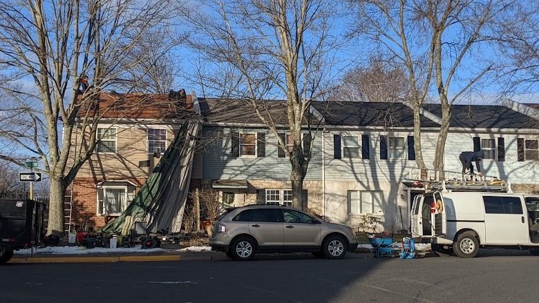 Row houses with a vehicle and equipment parked in front during renovation.