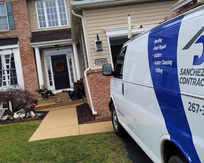 Sanchez Contracting van parked outside a two-story house with a brick facade. The van has a ladder on top.