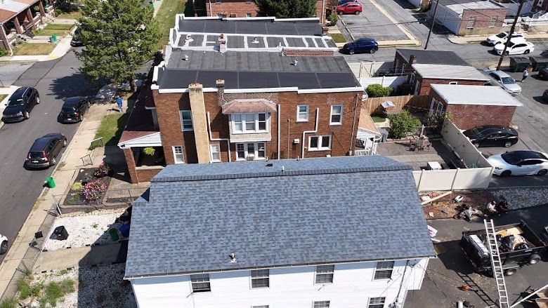 Aerial view of brick houses with solar panels on their roofs, parked cars, and a residential street.