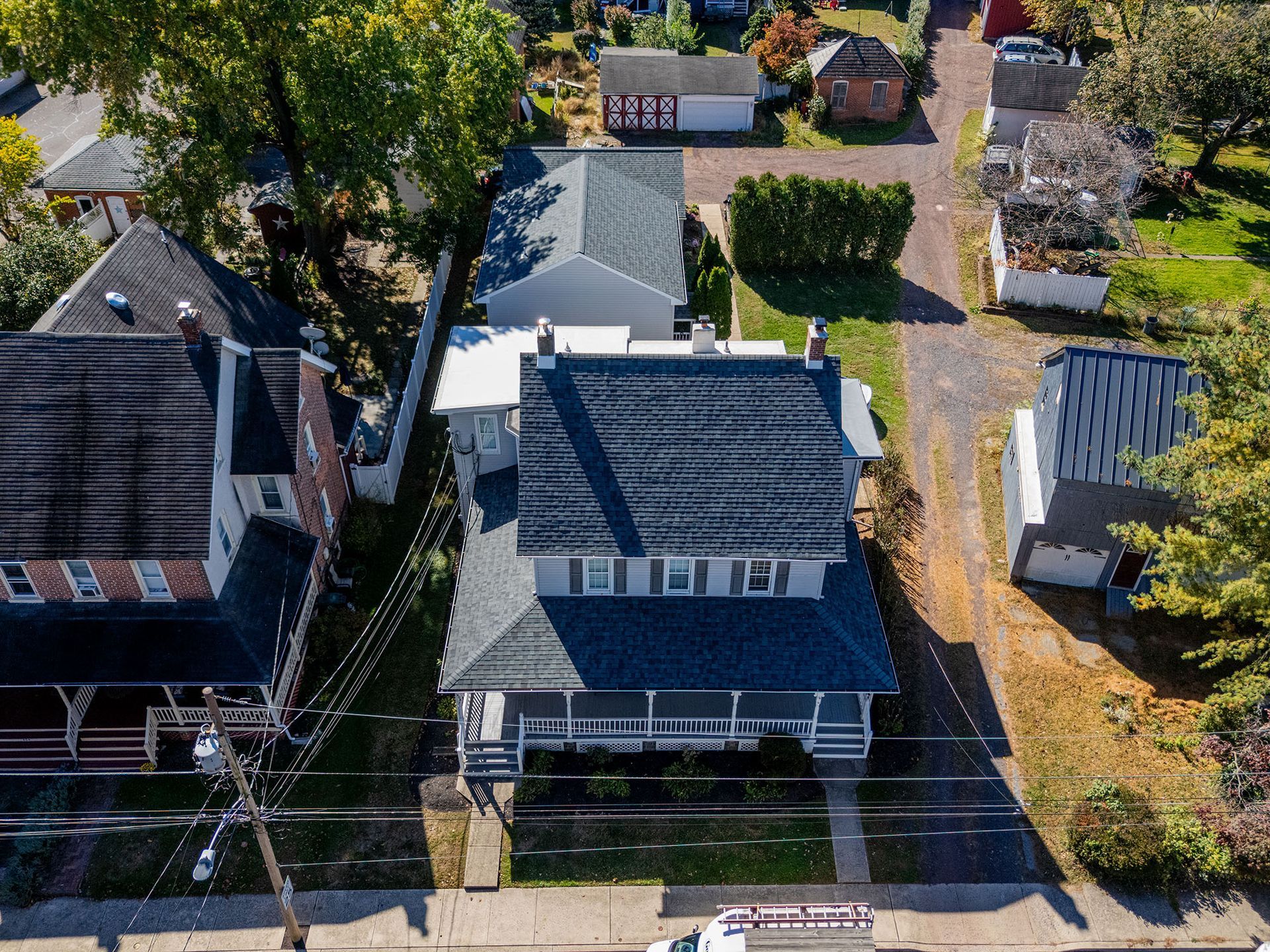 Aerial view of homes with dark roofs, green lawns, and a street.