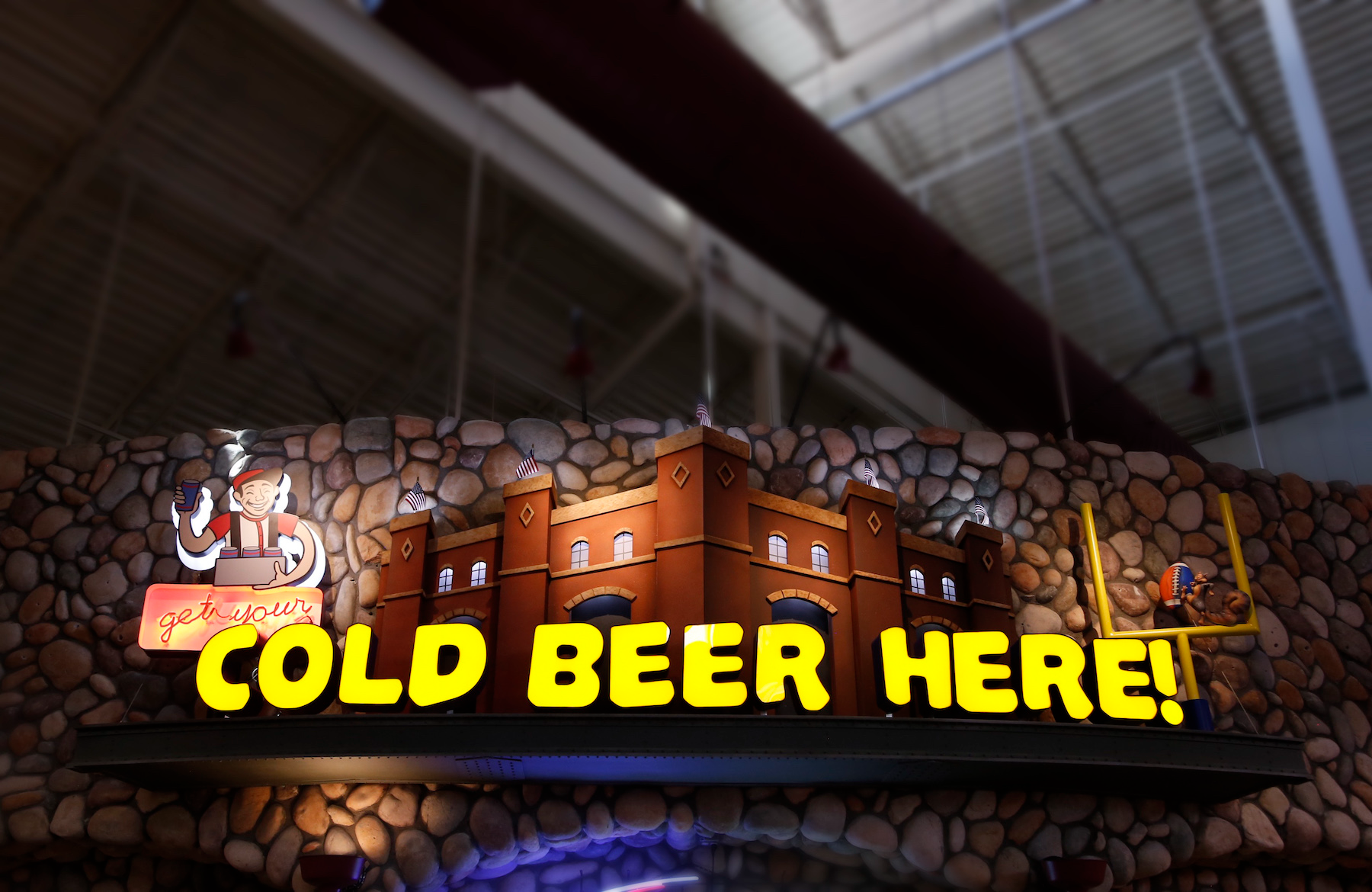 A sign hanging from the ceiling that says cold beer here