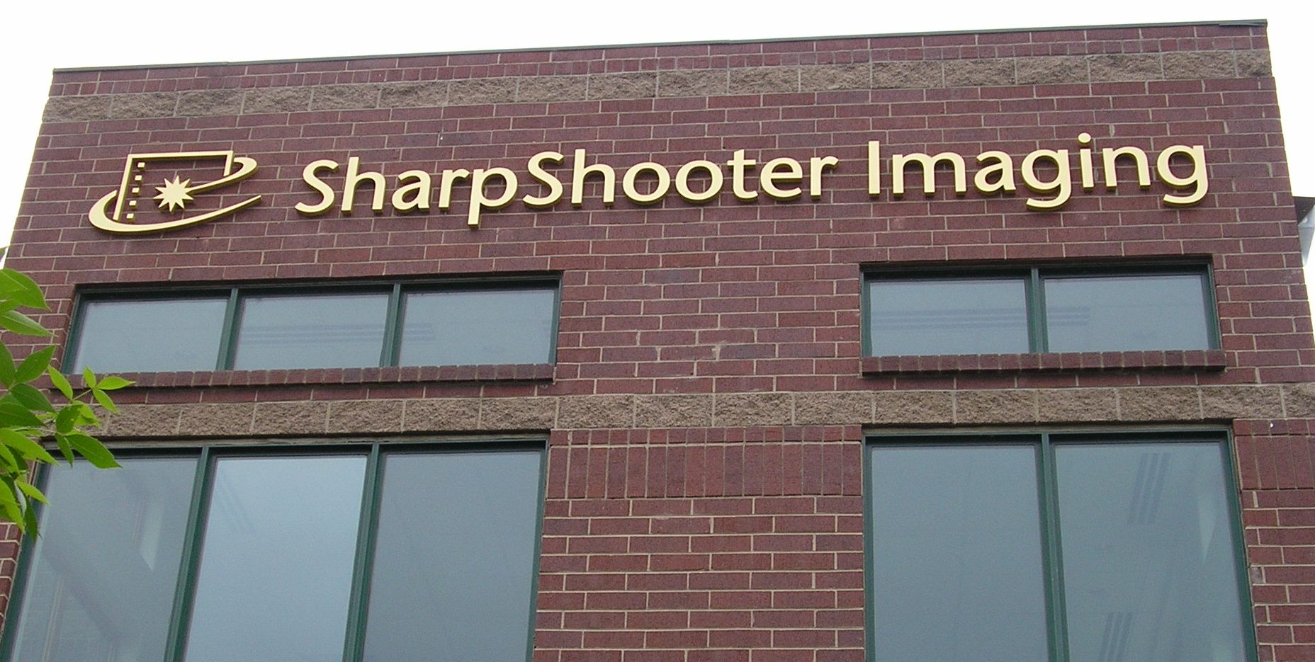 A brick building with a sign that says sharpshooter imaging