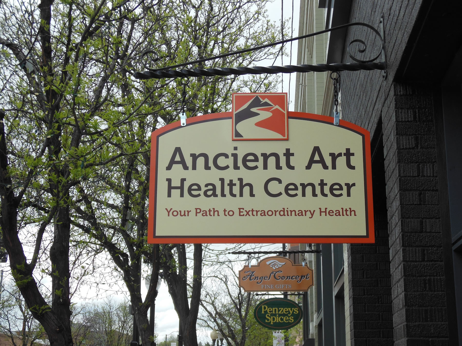A sign for the ancient art health center hangs from a building
