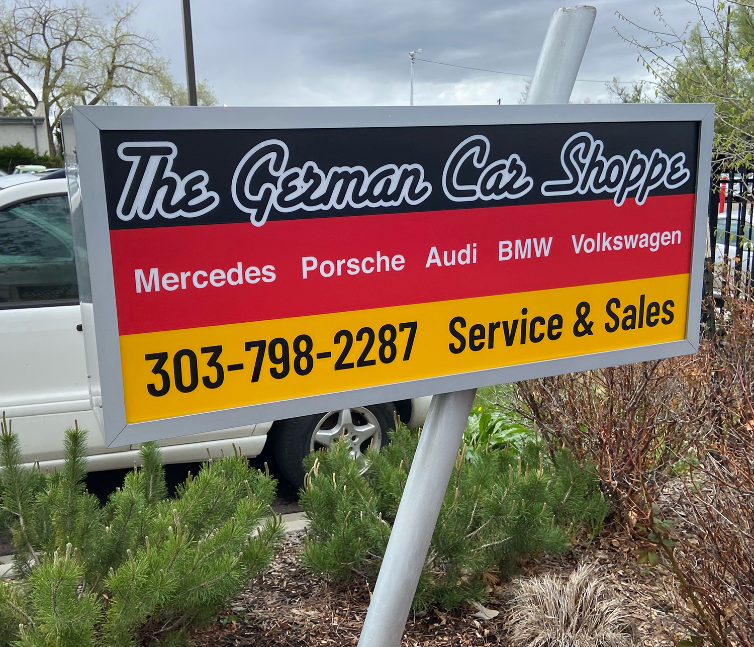 A sign for the german car shoppe with a phone number