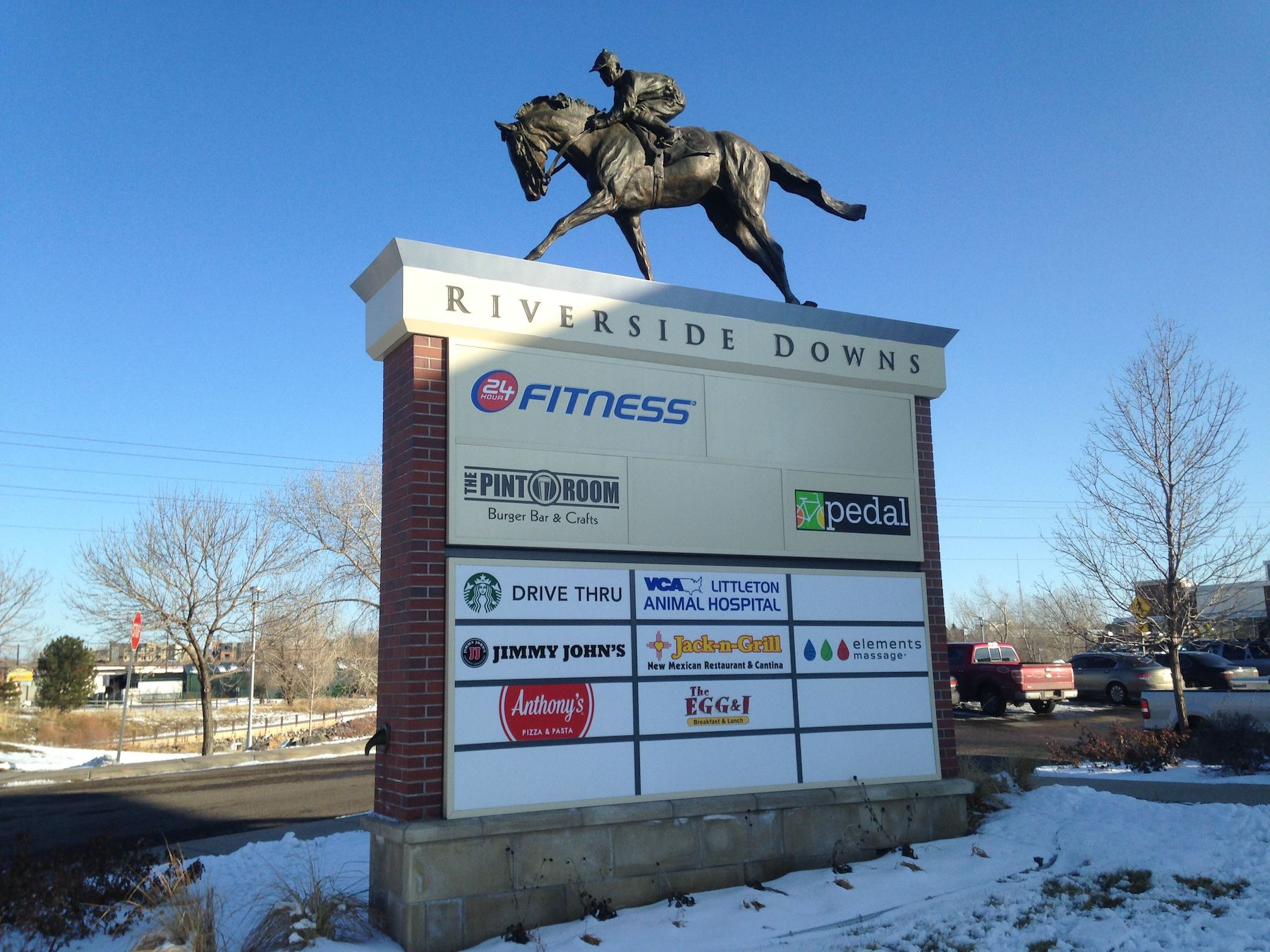 A sign for riverside downs with a statue of a man riding a horse