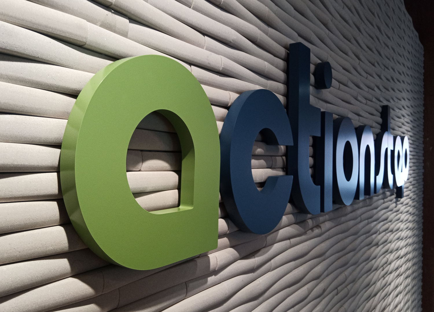 A green and blue sign that says action on a wall