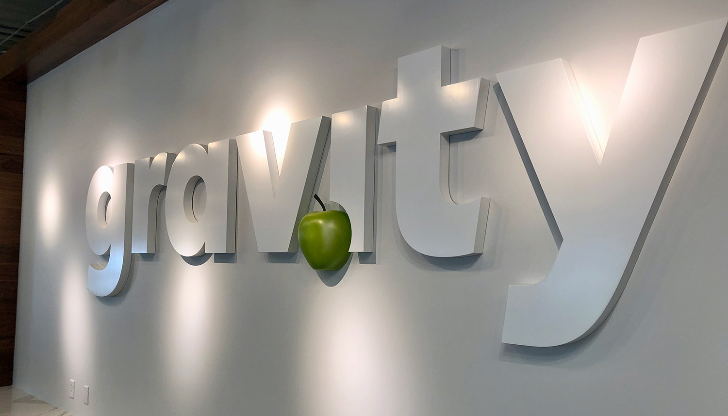 A sign that says gravity with a green apple on it