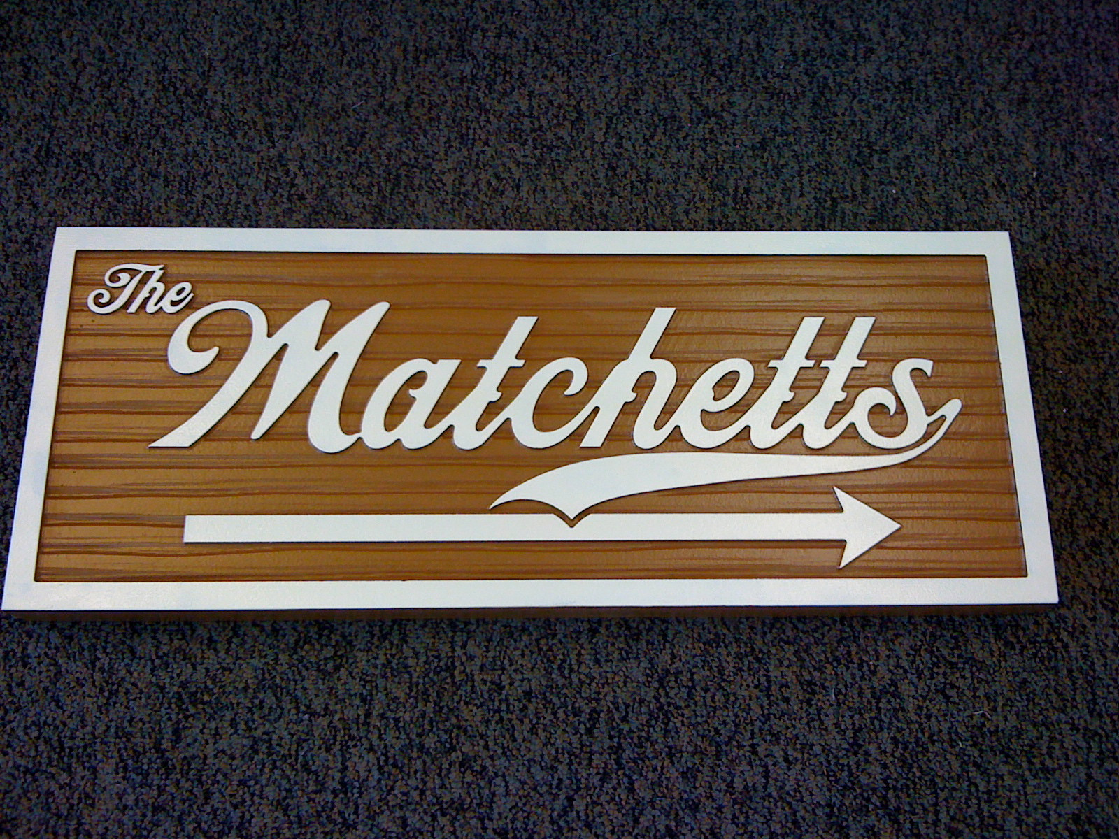 A wooden sign that says the matchetts with an arrow pointing to the right