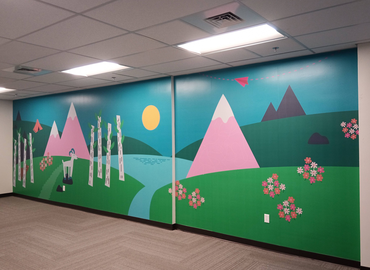 A wall with a painting of mountains and flowers on it