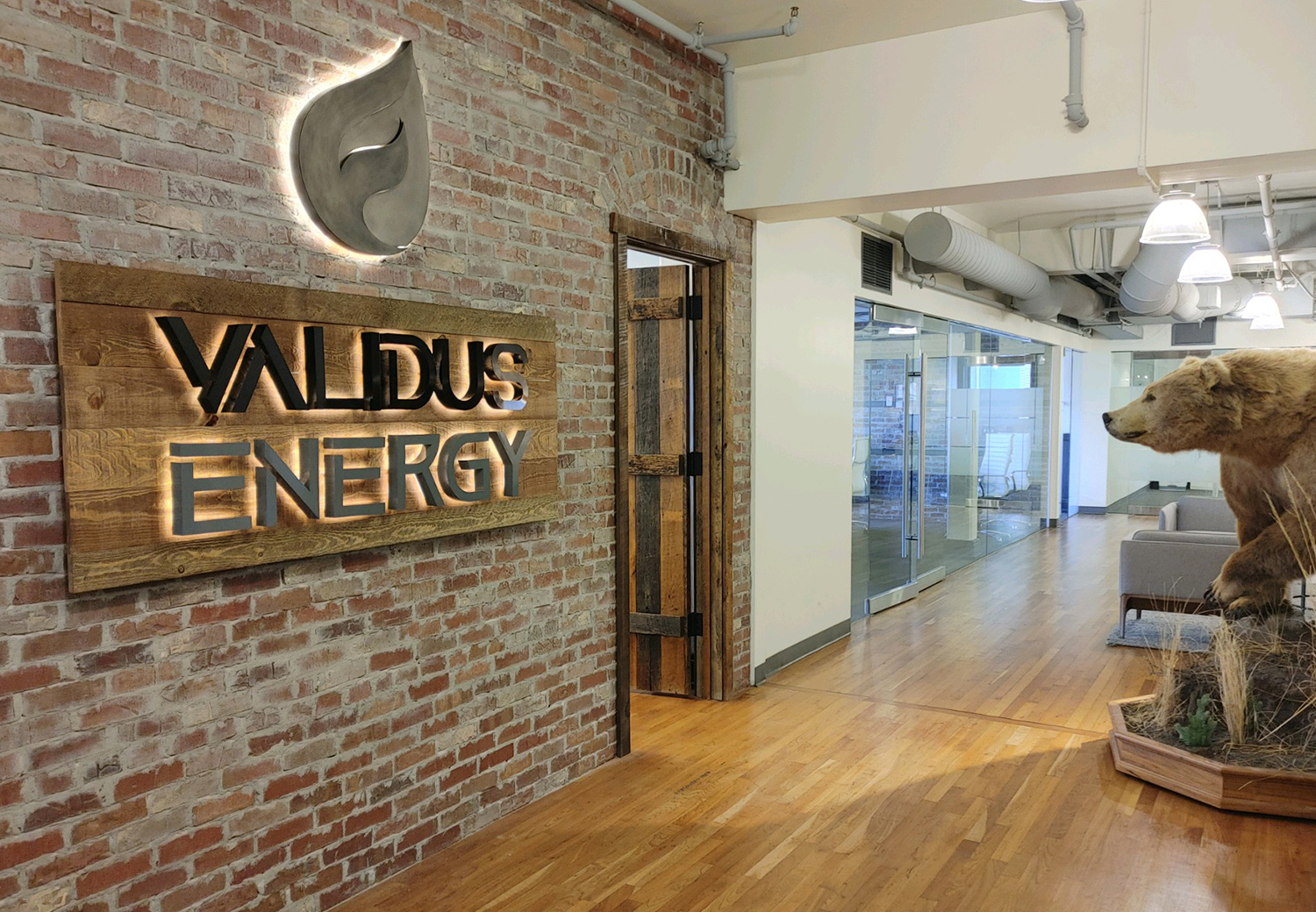 A wooden sign on a brick wall says valdus energy.