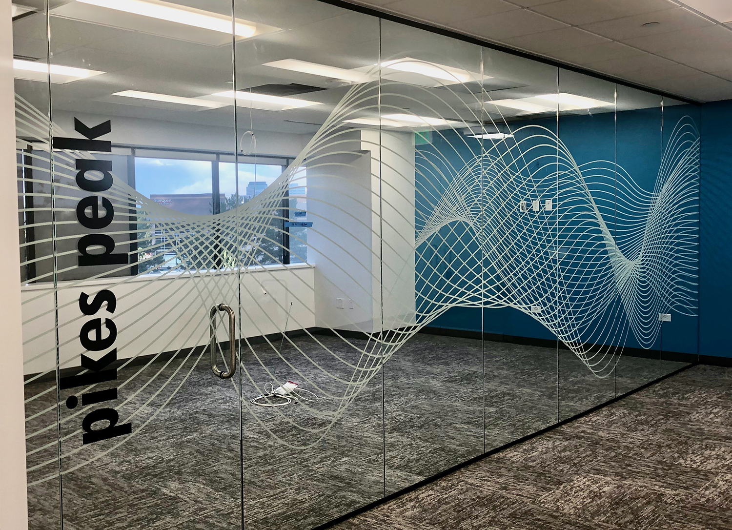 A room with a glass wall and a mural on the wall that says Pikes Peak