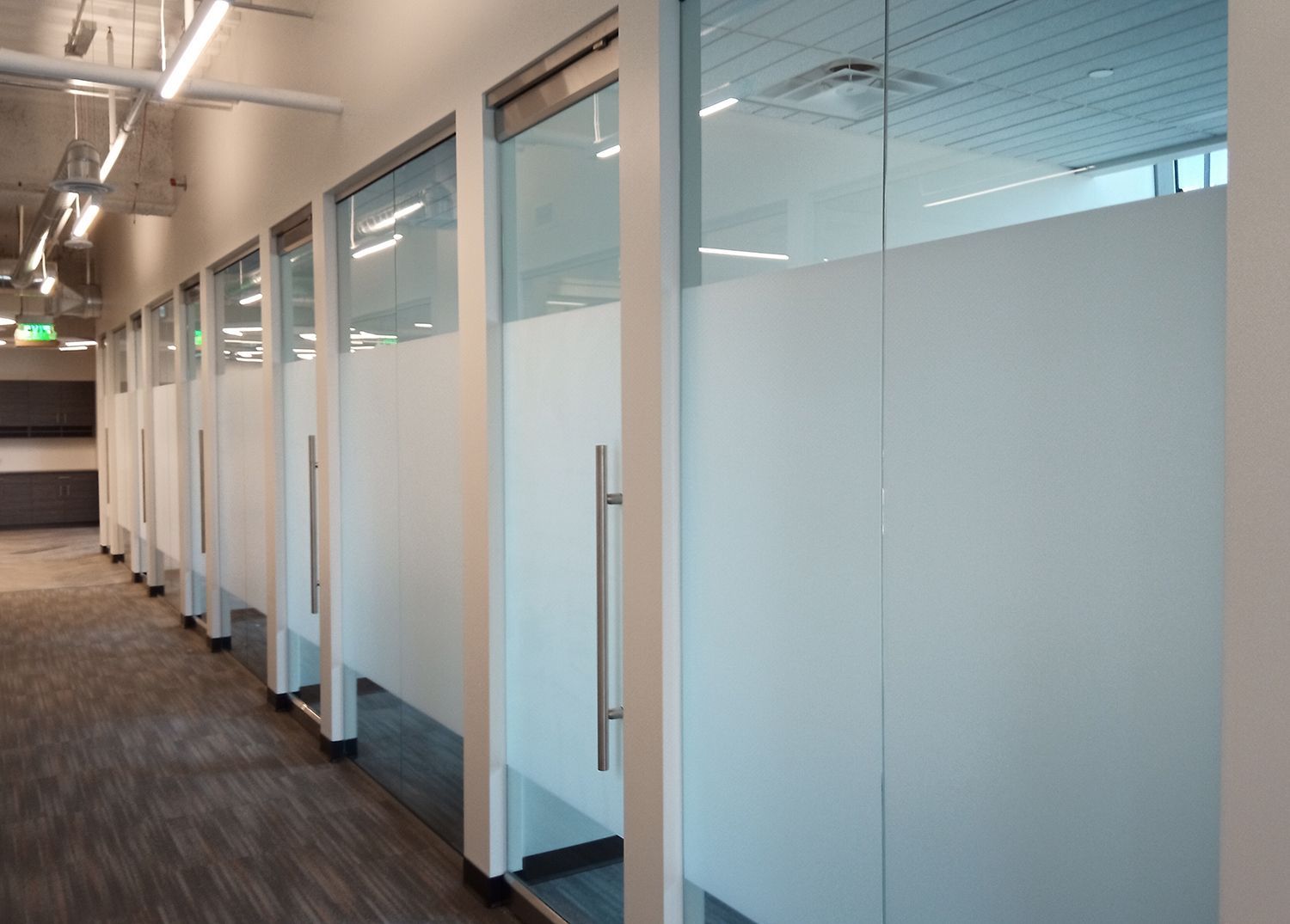A row of cubicles with glass doors in an office building