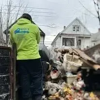 Person in green hoodie near overflowing debris pile; residential setting.