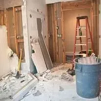 Bathroom remodel with rubble, ladder, and a blue trash can.