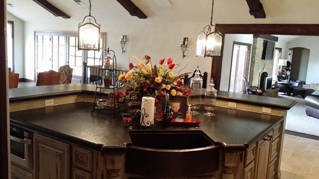 Kitchen with dark countertops, farmhouse sink, and large floral arrangement.