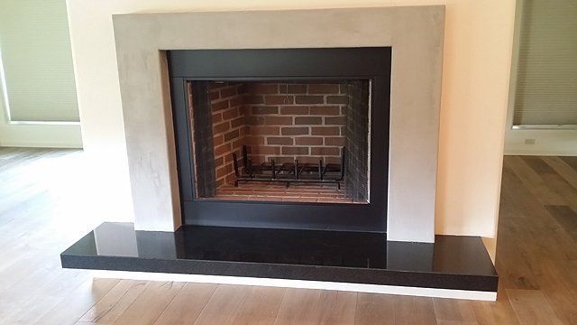 Fireplace with black and gray surround and black hearth. Brick firebox.