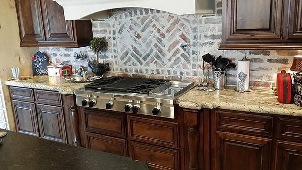 Kitchen with dark wood cabinets, granite countertops, and brick backsplash over a stovetop.