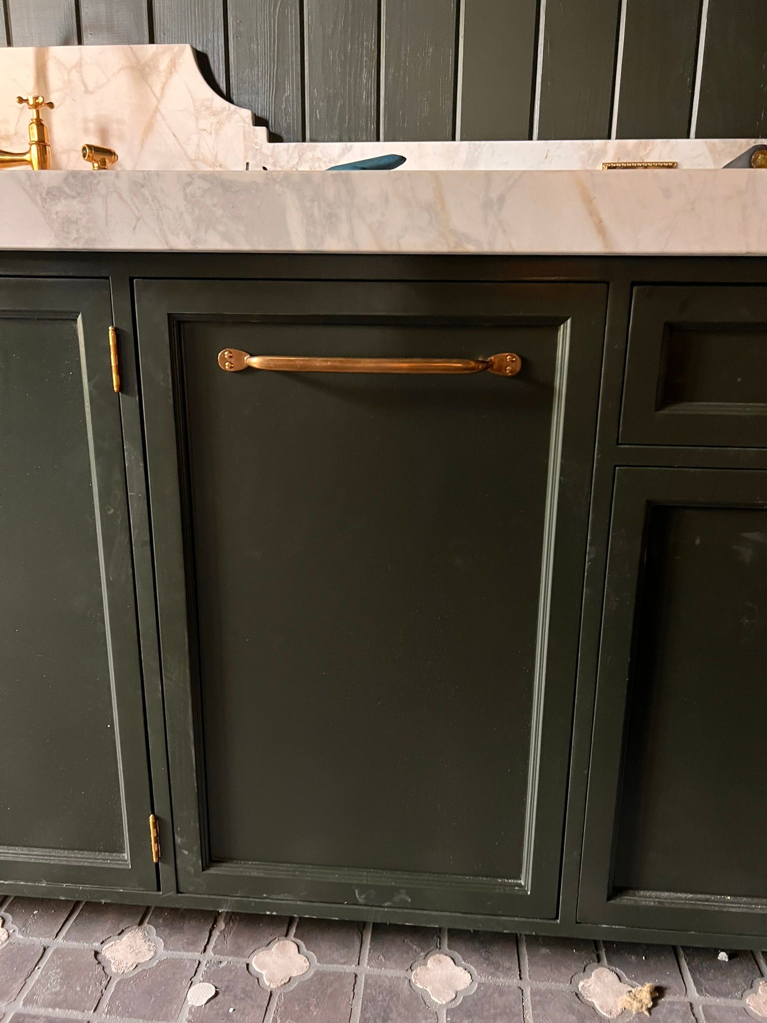 Dark green cabinet with gold hardware under a white countertop.
