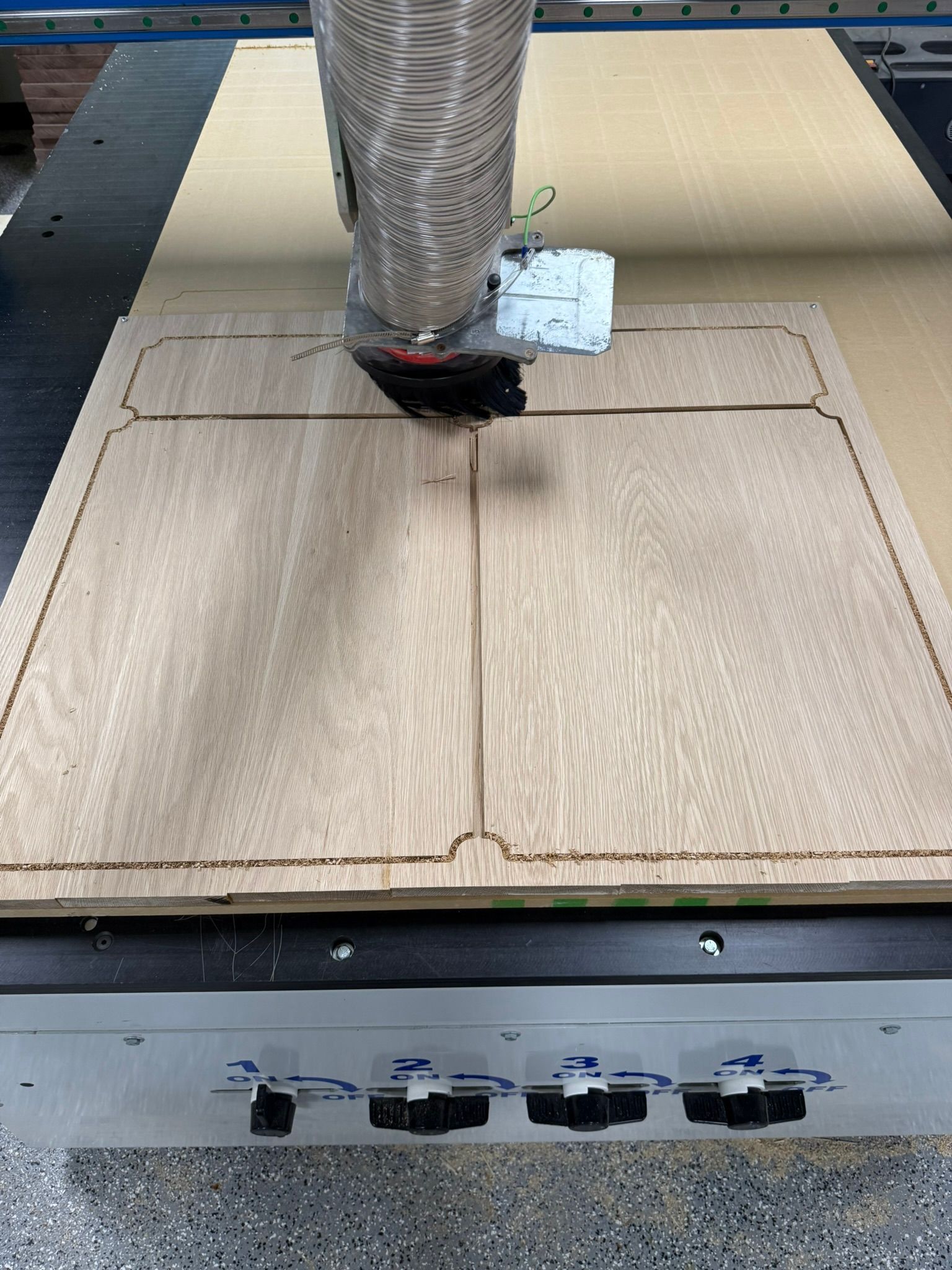 CNC machine cutting a wood panel, following a pre-set pattern.
