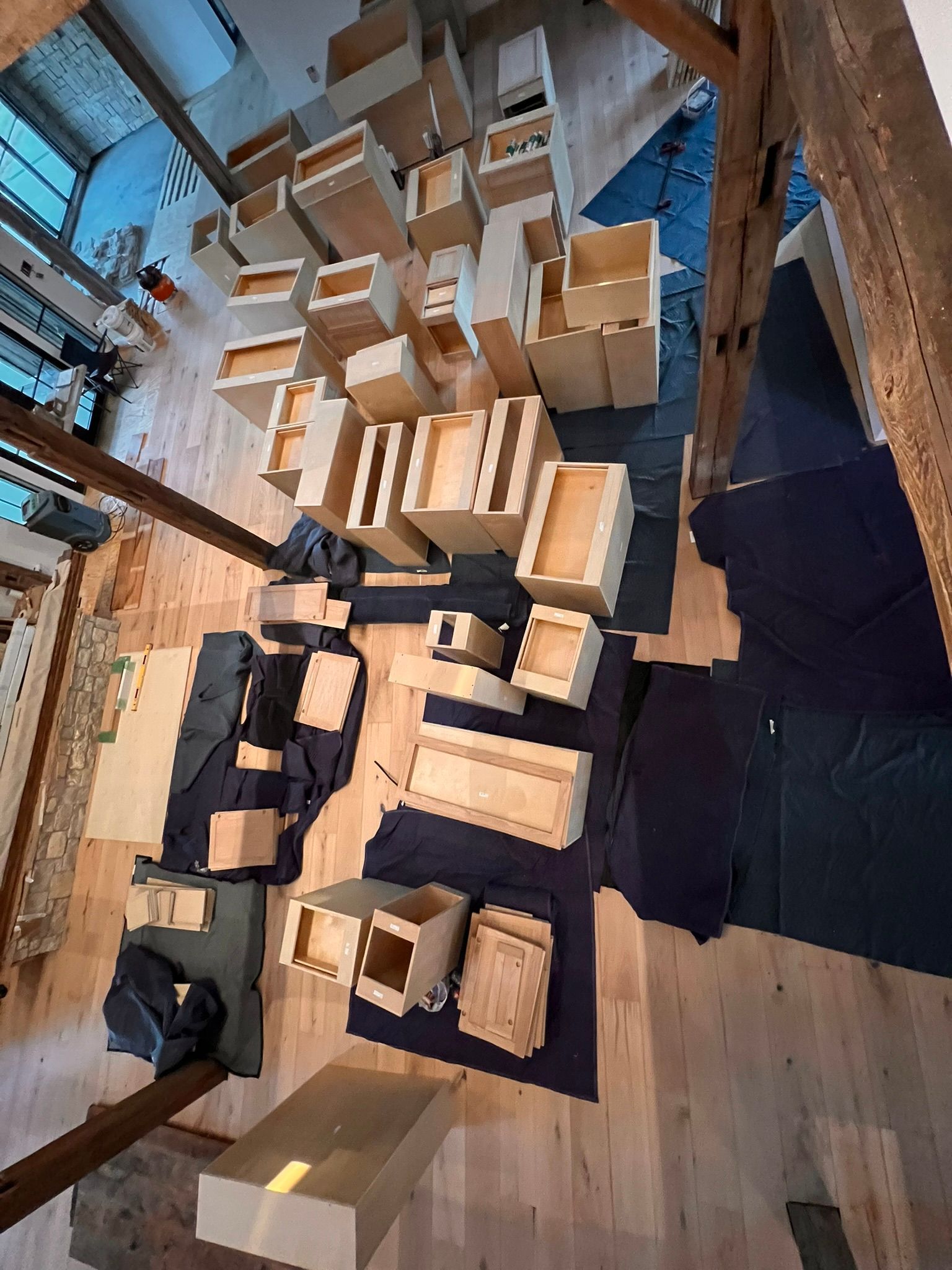 Overhead view of wooden drawer boxes and parts laid out on a wooden floor, possibly for assembly.