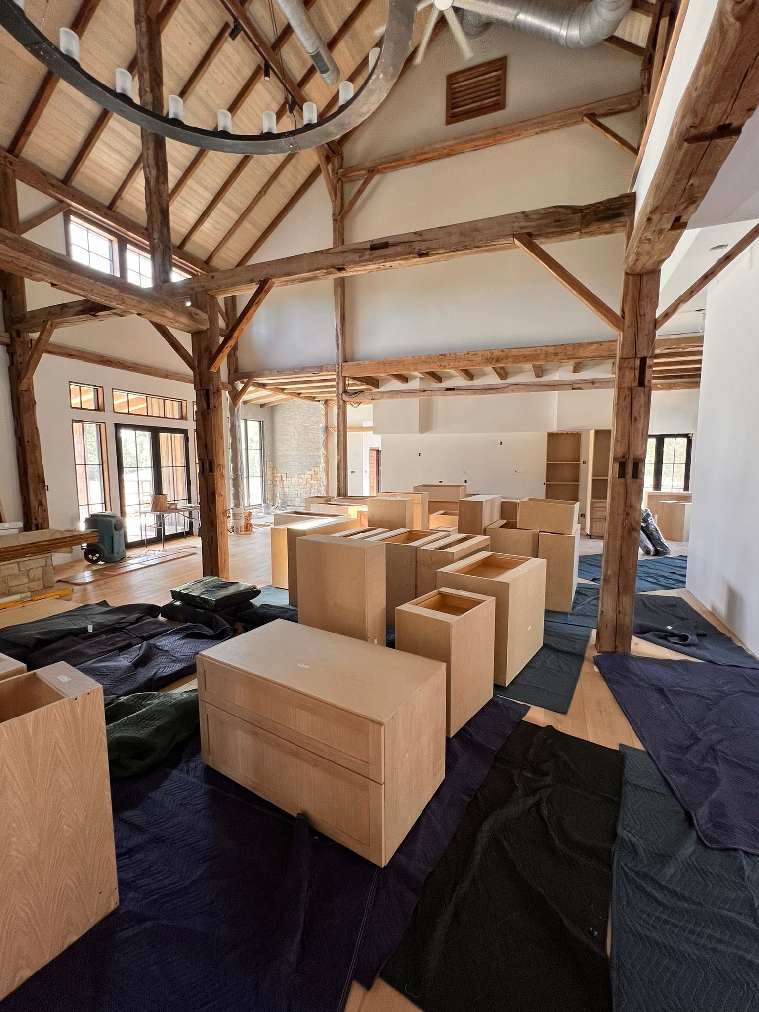 Interior of a large room with exposed wooden beams, unfinished walls, and boxes scattered on the floor.