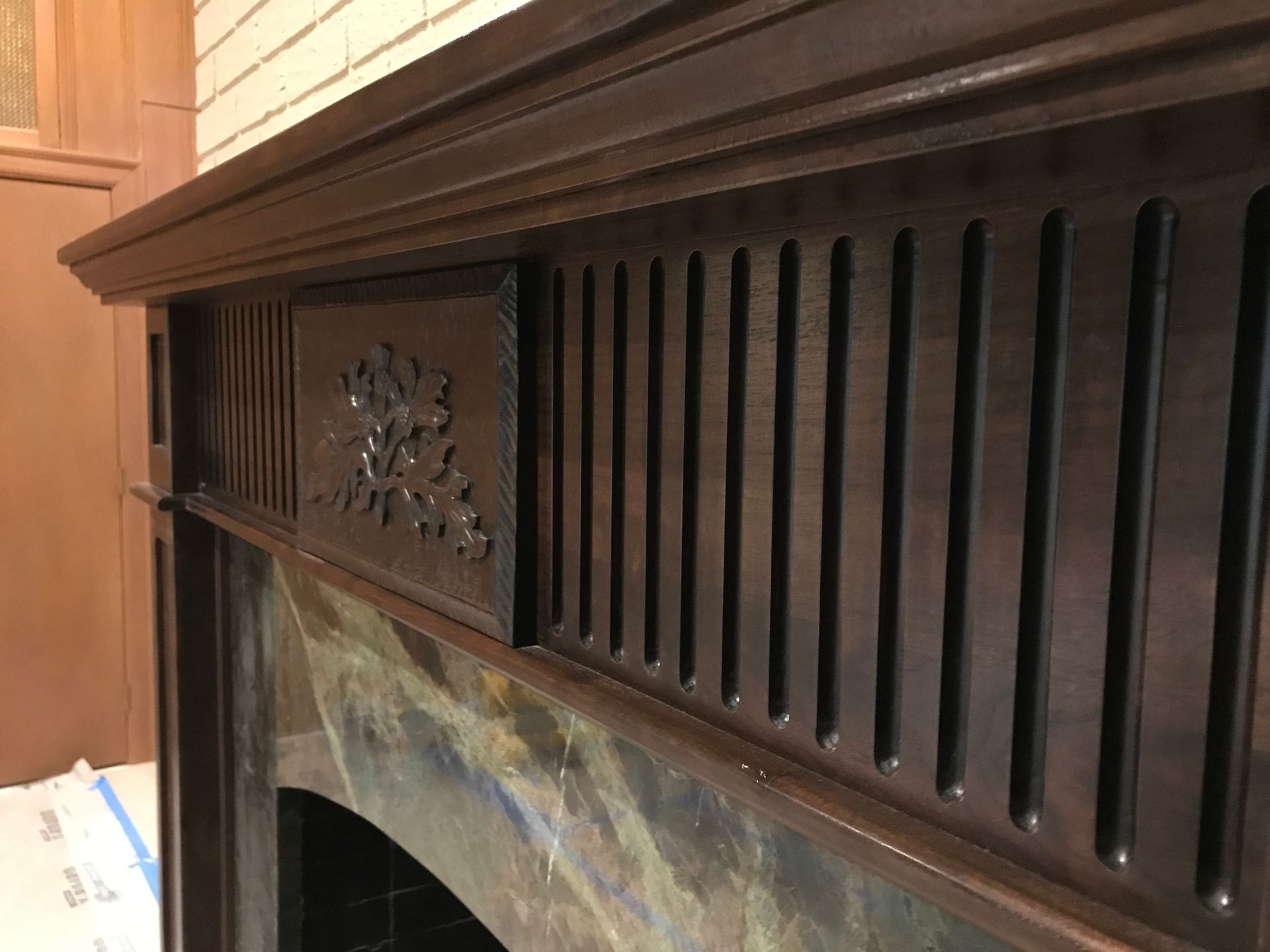 Dark wooden fireplace mantel with carved details and a green marble hearth.