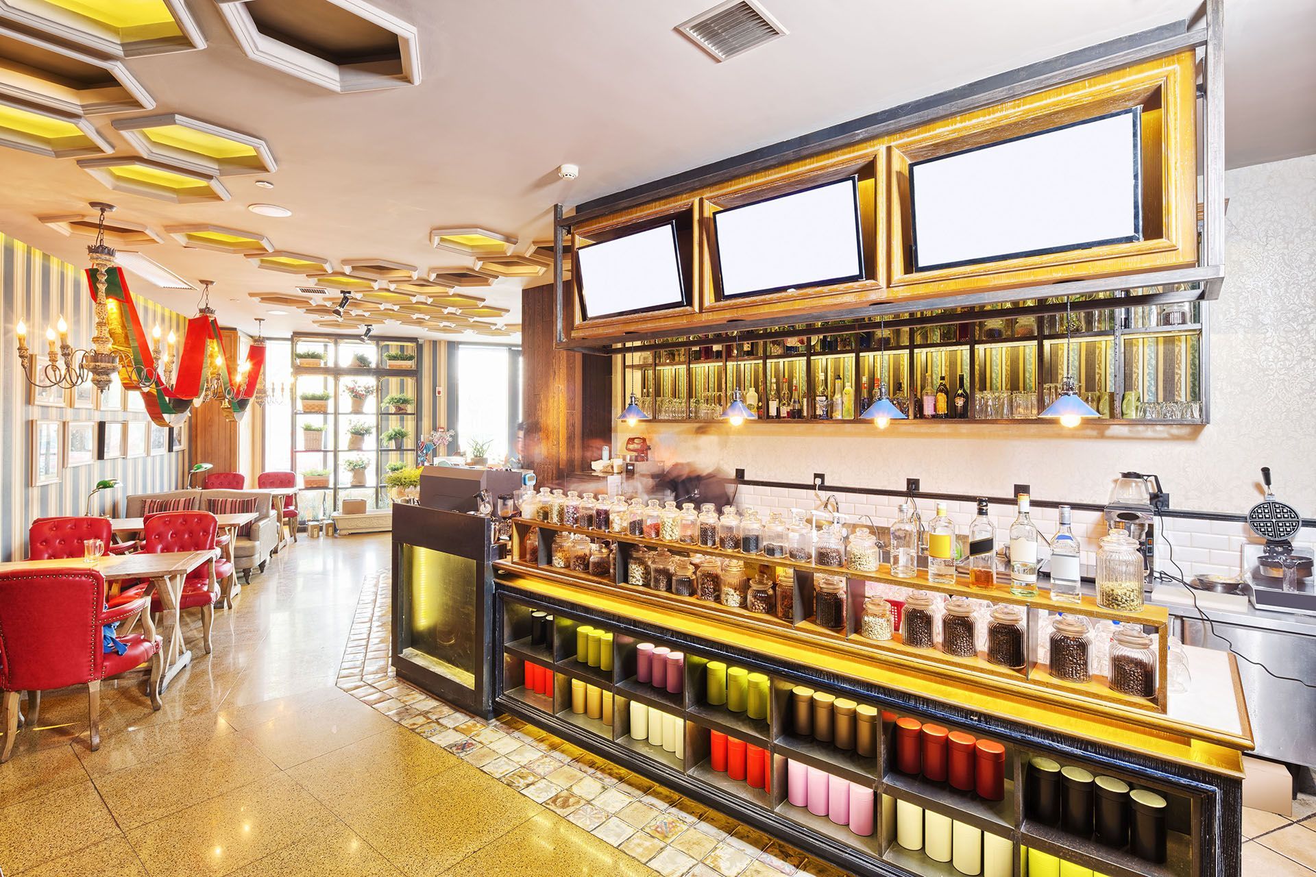 Bright modern bar with red chairs, mirrored shelves, and warm lighting in a stylish restaurant interior